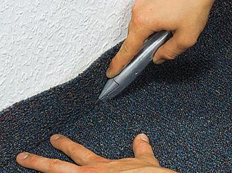 Teppich kleben: Teppich in Winkel zwischen Wand und Boden druecken